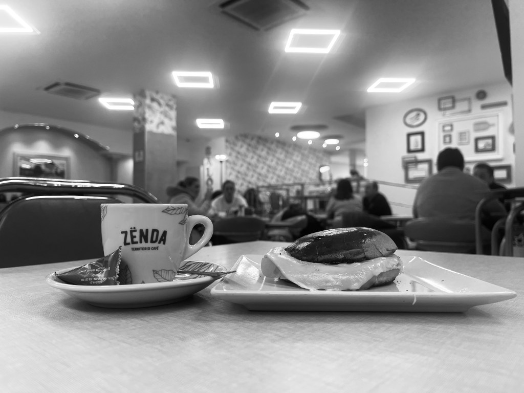 A black coffee with a warm cheese and ham slider in Olympia Cafeteria Pasteleria, Granada, Spain.